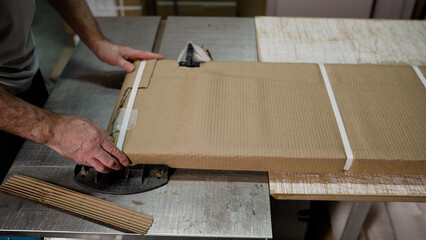 Cardboard in the warehouse, packaging of furniture fittings. Empty boxes for packaging. Tape wraps around a cardboard box at a furniture factory.