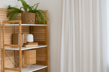 Folding screen, wooden shelving unit with books and houseplant in wicker pot