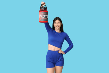 Sporty young woman holding bottle with protein cocktail on color background
