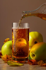 Apple cider is poured from a bottle into a glass.