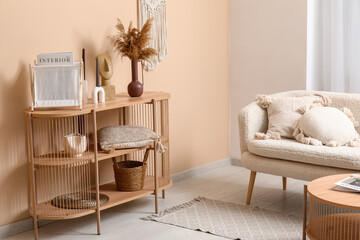 Comfortable sofa and shelving unit with different decor near beige wall in interior of modern living room