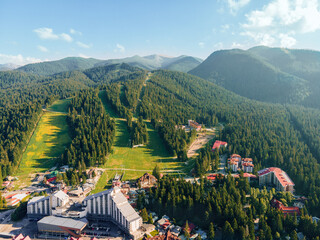 Resort mountain cottages for tourists, Borovets, Bulgaria. Town located in mountains among green forests, top view. Aerial view red roofs of cottage houses in a clearing in forest. Nature holiday