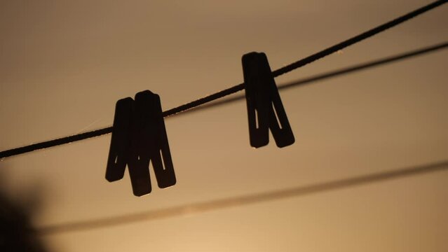 Silhouette Of A Plastic Clothespins Hang In A Row On The Rope