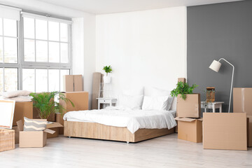 Cardboard boxes with bed in room on moving day