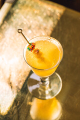 yellow sparkling drink in wine glass with candies on cocktail pick