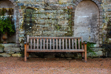 Wooden bench in front of a stone wall.