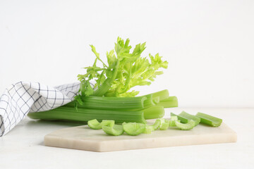 Board with fresh green celery on white background