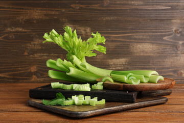 Boards and plate with fresh green celery on wooden background