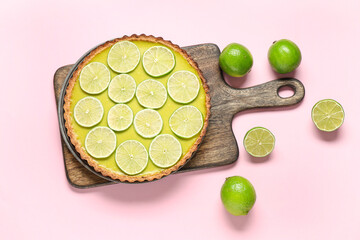 Wooden board with tasty lime tart on pink background