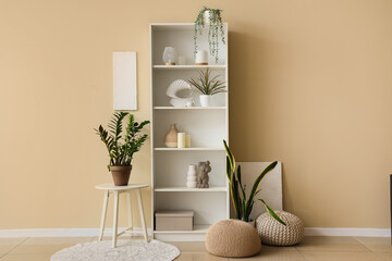Shelving unit with houseplants near beige wall in living room