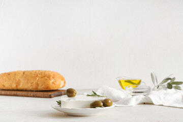 Plate with tasty feta cheese, olives and rosemary on white background
