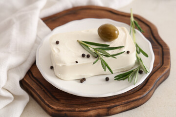 Plate with tasty feta cheese, olive, rosemary and peppercorn on white background
