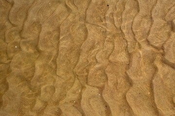 Ocean water texture background. Top view of the sandy seabed. Shallow water surface.