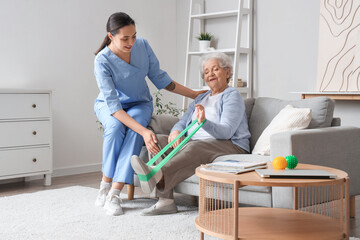 Senior woman training with stretching band and physical therapist at home