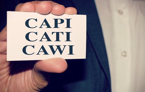 Business man holding a paper with the words "Capi" Computer Assisted Personal Interviewing, "Cati" Computer Assistes Telephone Intevierwing "CAWI" Computer Assisted Web Interviewing.