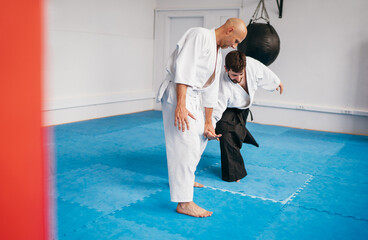 Two men are practicing Aikido in dojo wearing traditional white Kimono and Hakama .One man executes...