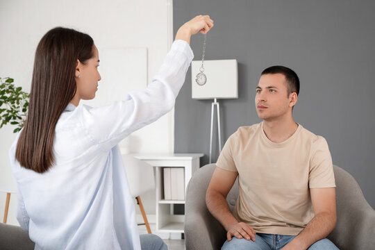 Young man sitting in armchair during hypnosis session at psychologist's office