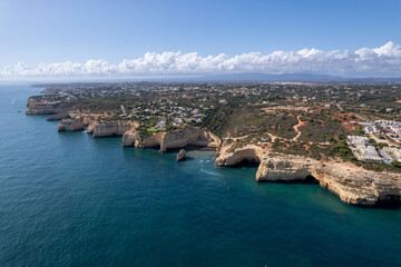 Benagil in Portugal - view of caves and cliff and coast from the ocean - cumulus clouds - blue ocean - drone view - birdeye view