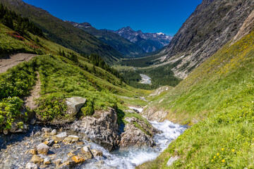 Obraz premium Tour du Montblanc beautiful mountain ladscapes of the Alps green valley, snow summit of Montblanc and rocky peaks of Aiguille du Midi in summer sunny weather blue sky, trekking and hiking in Chamonix
