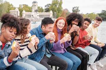 Diverse group of young people having a snack together and sharing good times. Concept: friendship