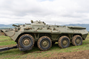 Fototapeta premium Russian armored personnel carrier in green camouflage attached to a tractor