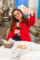A young beautiful lady travels through a European city. Vacation vacation in Europe. Red raincoat blue denim overalls, sunglasses, happy mood