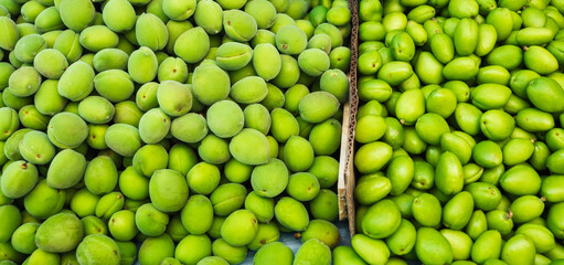 unripe green apricot on counter of the bazaar. Traditional food in Central Asia in Uzbekistan and Tajikistan - green uryuk, dovcha, gura