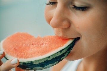 A woman is eating a watermelon slice