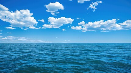 Obraz premium Vibrant image of the open ocean under a blue sky dotted with cumulus clouds, representing nature's vastness