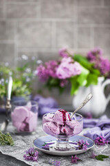 Cup of delicious homemade blueberry icecream and lilac on background