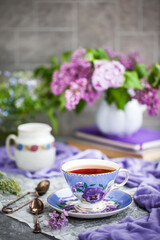 Purple cup of tae and lilac on gray background