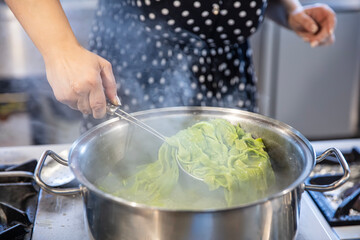 Spinach Green Pasta. Spinach pasta. Female chef throws green spinach pasta dough into a boiling pot...