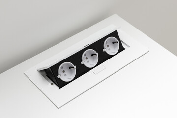 White built-in electric socket with ports on a white table. A group of European electrical sockets...
