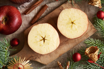 Cut apple with a star in the middle, with Christmas tree branches on a table