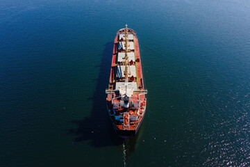 Bulk vessel for dry cargo cruising in sea for loading in industrial port, aerial shot