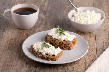 Homemade rye bread with cottage cheese in a plate and coffee. Healthy breakfast concept