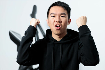 A young man celebrating success in then gym, expressing happiness and triumph with fists in the air