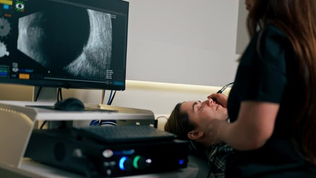 in an ophthalmology clinic young doctor performs an ultrasound of the eye of a young girl