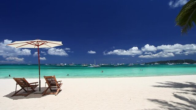Sun umbrellas and beach chairs on tropical beach with palm trees. Summer vacation. Boracay