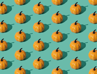 Trendy autumn or fall pattern made with orange pumpkins on green background. Minimal autumn composition. Nature flat lay. Season concept. Pumpkin aesthetic.