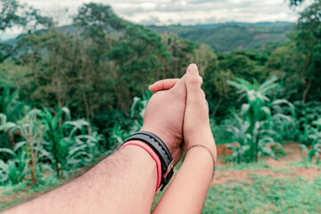 close-up of the intertwined hands of a man and woman couple. The man is wearing a black watch