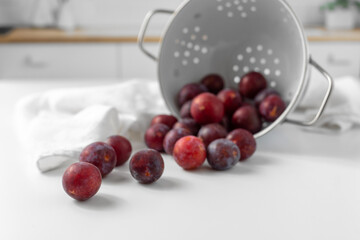 Close Up of  Red Plums Poured Onto a White Kitchen Counter