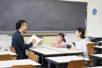面談を受ける親と子供　小学校の教室での三者面談のイメージ