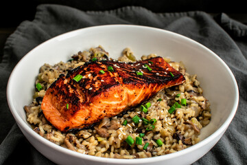 Seared Salmon with Mushroom Risotto in a Pasta Bowl: Marinated salmon fish fillet on a bed of mushroom risotto with scallions and sesame seed garnish