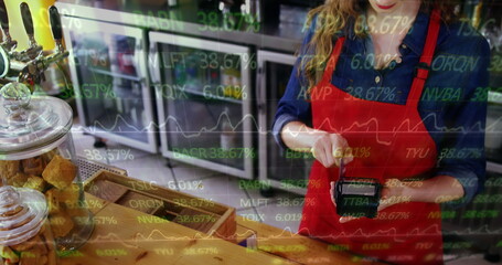 Image of financial data processing over woman holding paying terminal swiping credit card