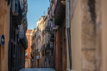 Fototapeta premium Walking through a Narrow Street with Charming Historic Buildings and Balconies under a Clear Sky