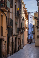 Walking through a Narrow Street with Charming Historic Buildings and Balconies under a Clear Sky