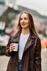 Fototapeta premium Urban Stroll with Coffee in Hand: A Woman Enjoys the City's Vibe