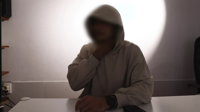 A man with a blurred face gives an interview