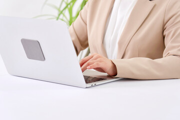 Fototapeta premium オフィスでパソコンを使ってデスクワークをする若いビジネスウーマン 顔無し